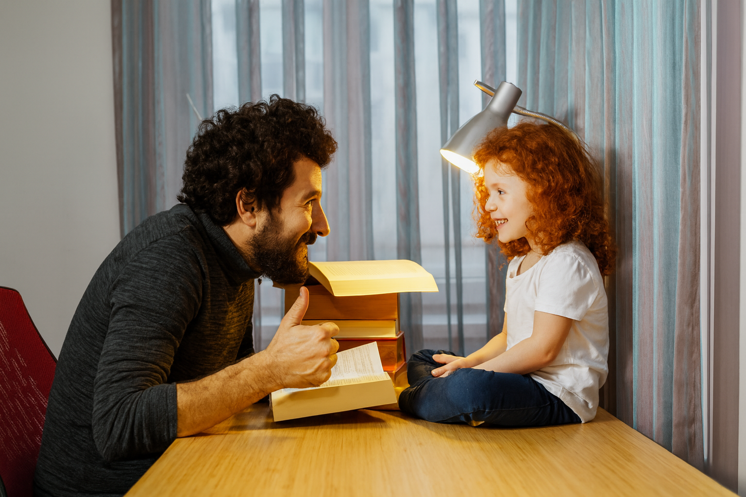 Father reading book to his son at desktop
